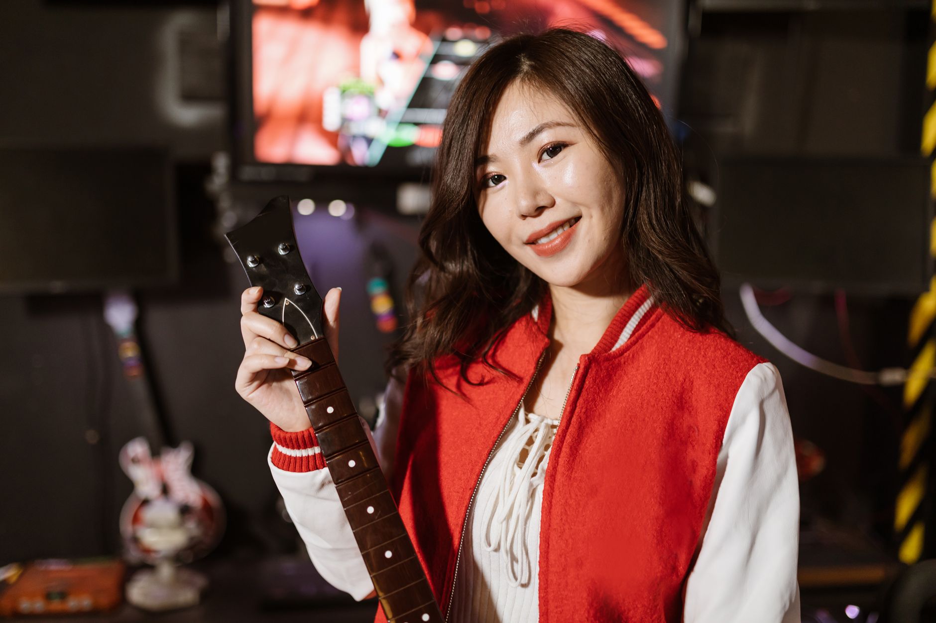 Young woman enjoying Guitar Hero game indoors, showcasing modern gaming and leisure activity.