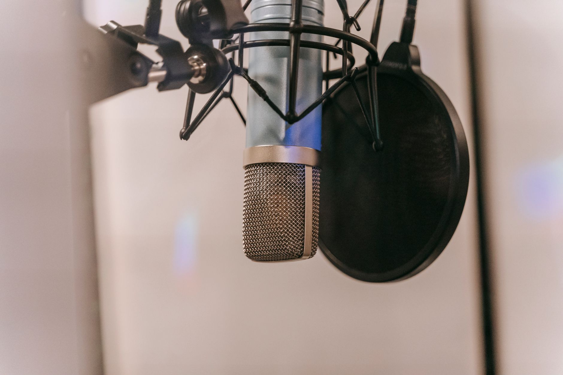 Close-up of a condenser microphone with pop filter in a studio setting, ideal for audio and podcasting.