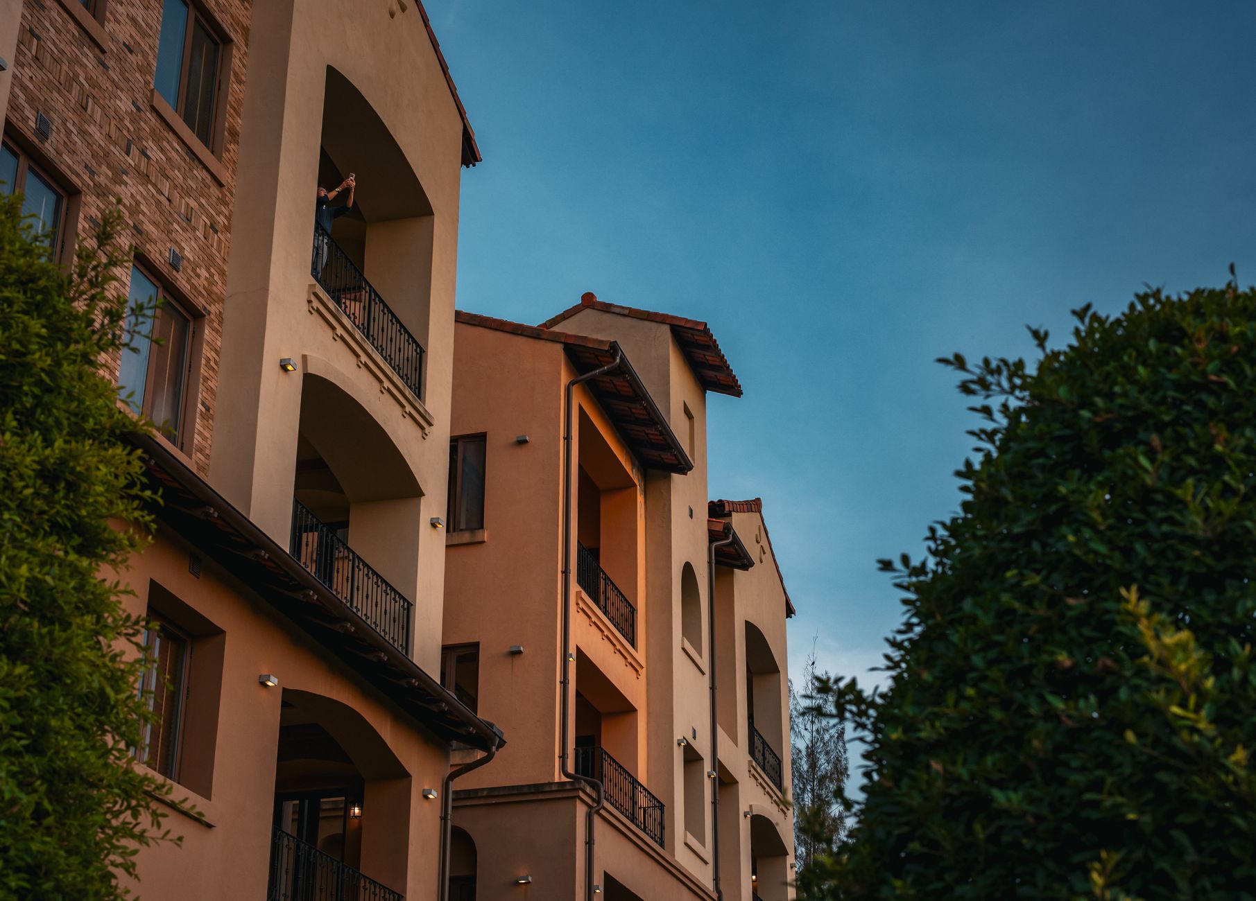 A stunning view of Italian-style architecture under the warm glow of a Thai sunset, framed by lush greenery.
