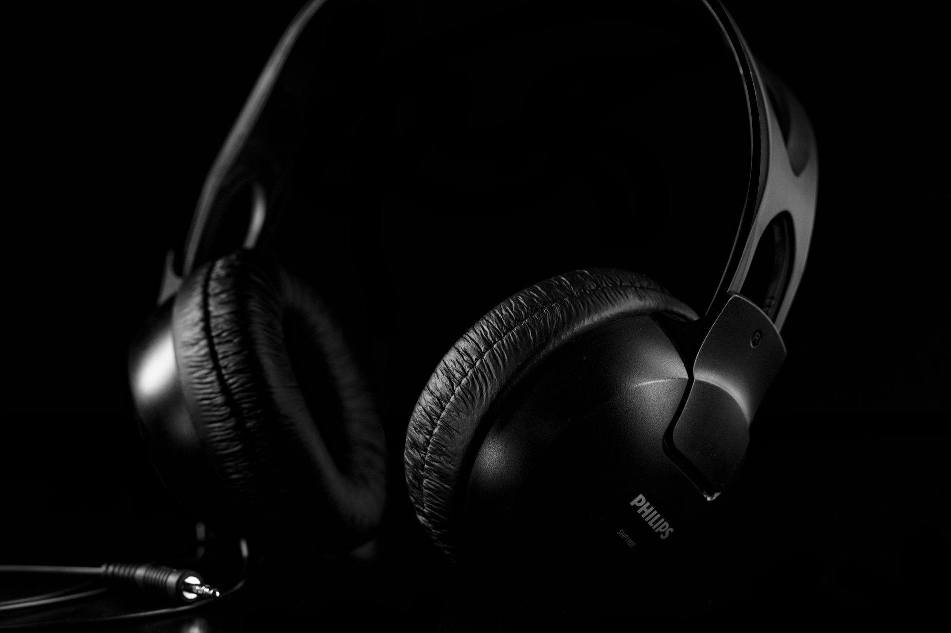 A detailed close-up of black headphones set against a dark background, showcasing design and texture.