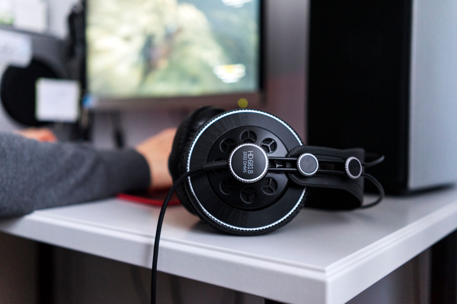 Black headphones resting on a desk in front of a blurred computer monitor. Modern workspace.