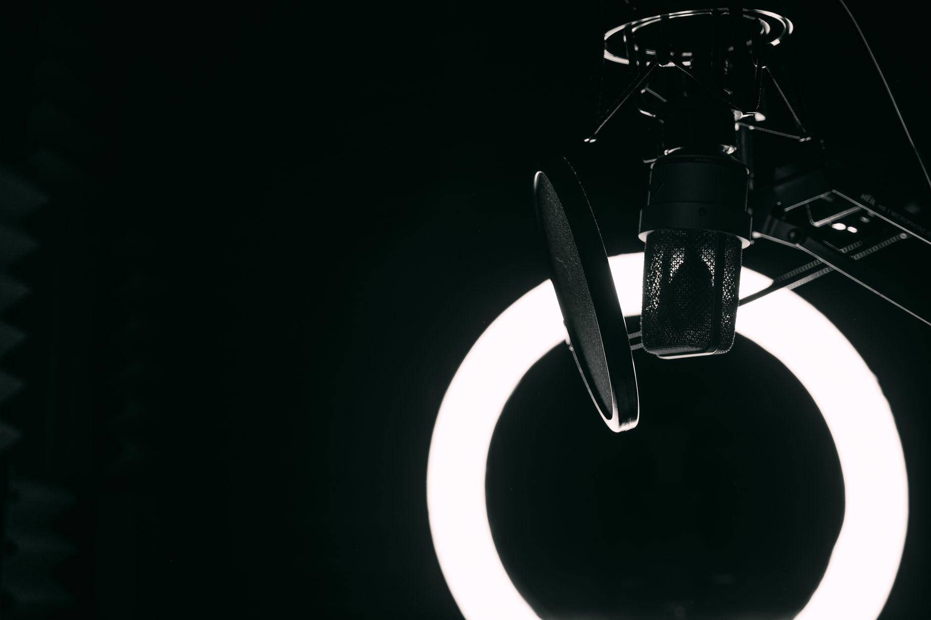 A close-up view of a microphone and ring light in a professional recording studio setting.